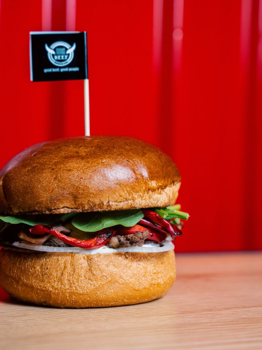 Good Beef bayraklı ev yapımı burger, kırmızı duvarlı salonda ahşap masada
